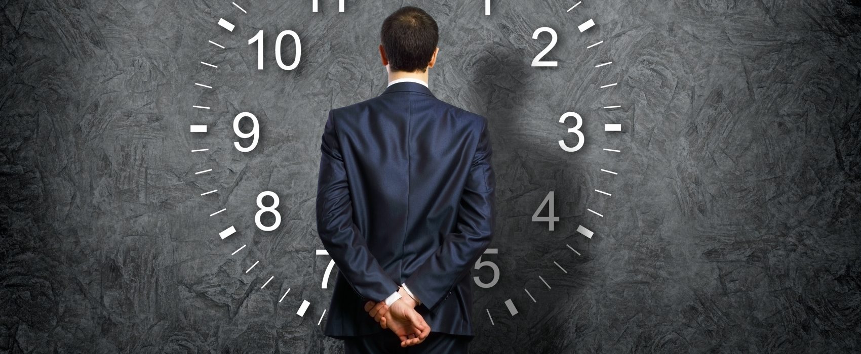 Man Looking At Giant Clock With His Back To Facing Us