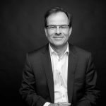 Black And White Corporate Style Head Shot Photo Of John Boynton Smiling