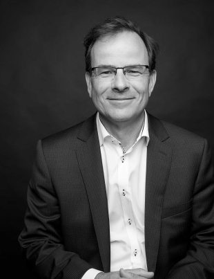 Black And White Corporate Style Head Shot Photo Of John Boynton Smiling