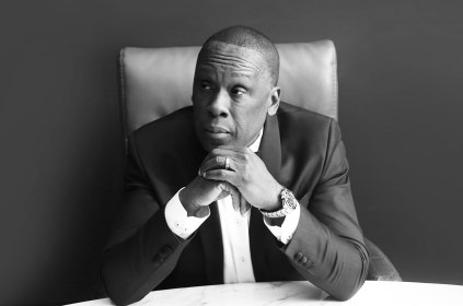 Black And White Photo Of Bruny Surin Sitting Down With Both Hands Under His Chin