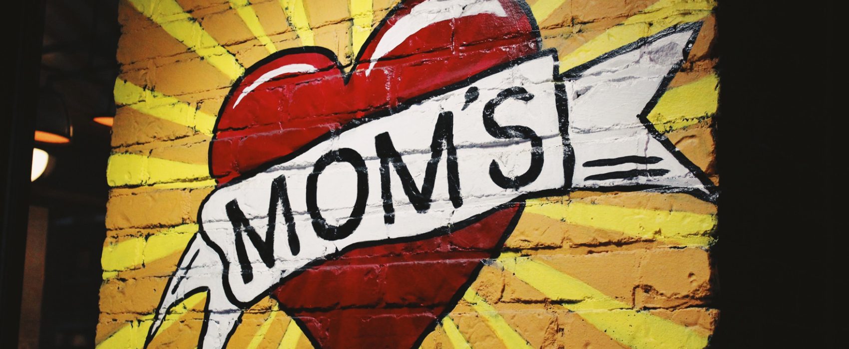 Heart With Word MOMs Across Heart Painted On Brick Wall