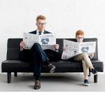Man And Young Boy Sitting On Sofa Each Reading A Business Newspaper